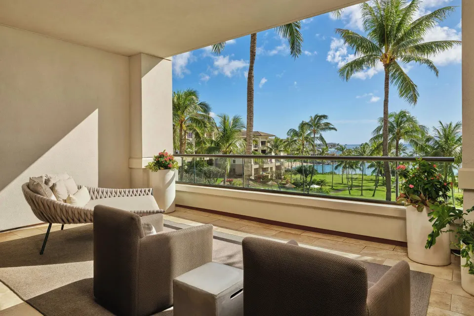 Covered balcony seating overlooking palm trees and distant ocean from the Signature 4 Bedroom Residence at The Resort at Kapa