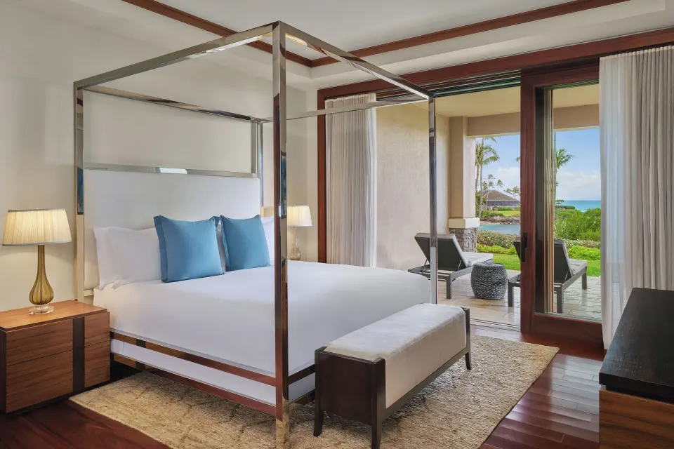 Bedroom with metal-framed canopy bed opening to patio and garden views at The Resort at Kapalua Bay, Maui