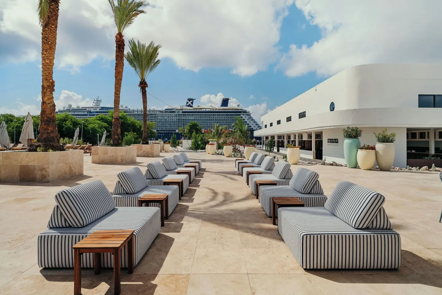 Outdoor lounge seating and palms at The Rif at Mangrove Beach Corendon Curacao, Curio.
