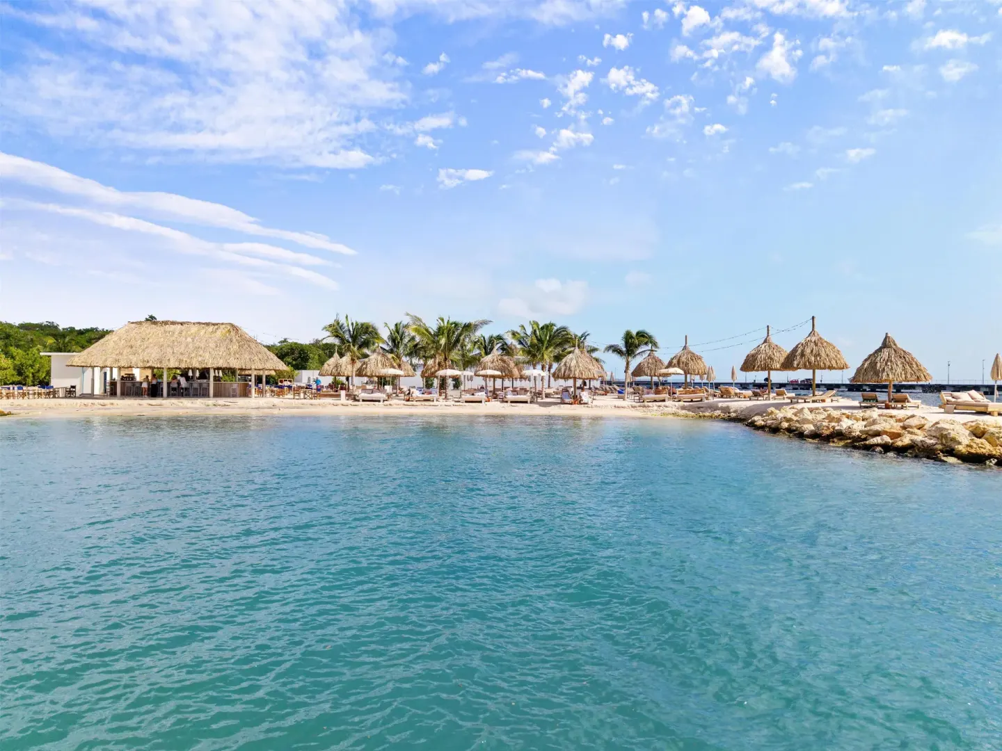 Turquoise waterfront with beach palapas at The Rif at Mangrove Beach Corendon Curacao, Curio.