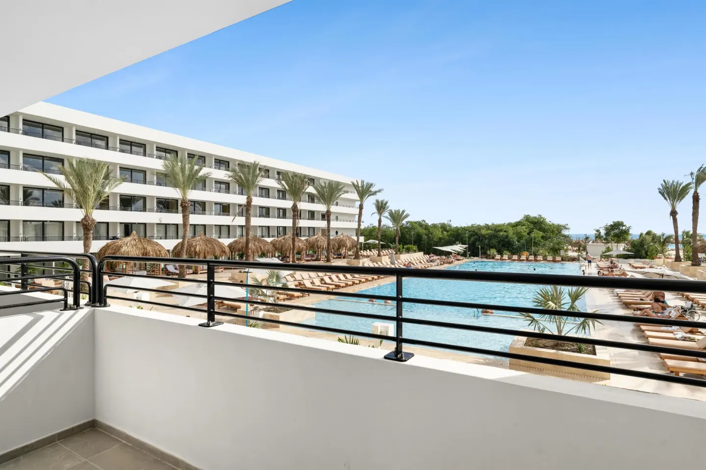 Balcony view over pool, palms, and resort buildings at The Rif at Mangrove Beach Corendon Curacao, Curio.