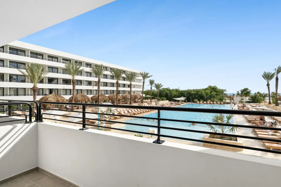 Balcony view over pool, palms, and resort buildings at The Rif at Mangrove Beach Corendon Curacao, Curio.