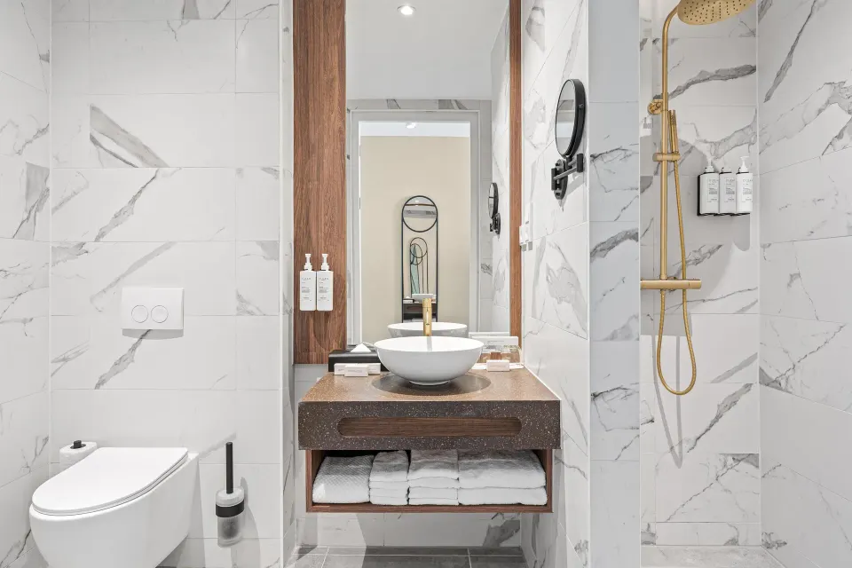 Bathroom with vanity, toilet, and shower in a Deluxe Room at The Rif at Mangrove Beach Corendon Curacao, Curio.