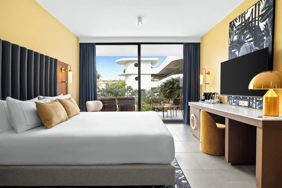 Deluxe Room king bed, desk, TV, and terrace at The Rif at Mangrove Beach Corendon Curacao, Curio.