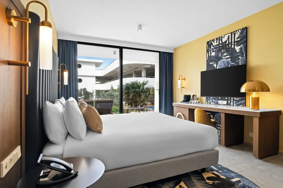 Deluxe Room king bed with TV wall and patio doors at The Rif at Mangrove Beach Corendon Curacao, Curio.
