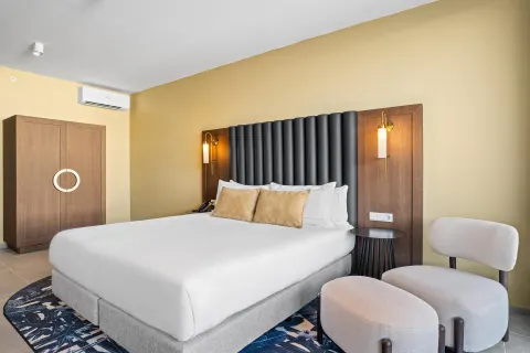 Deluxe Room king bed with lounge chair at The Rif at Mangrove Beach Corendon Curacao, Curio.