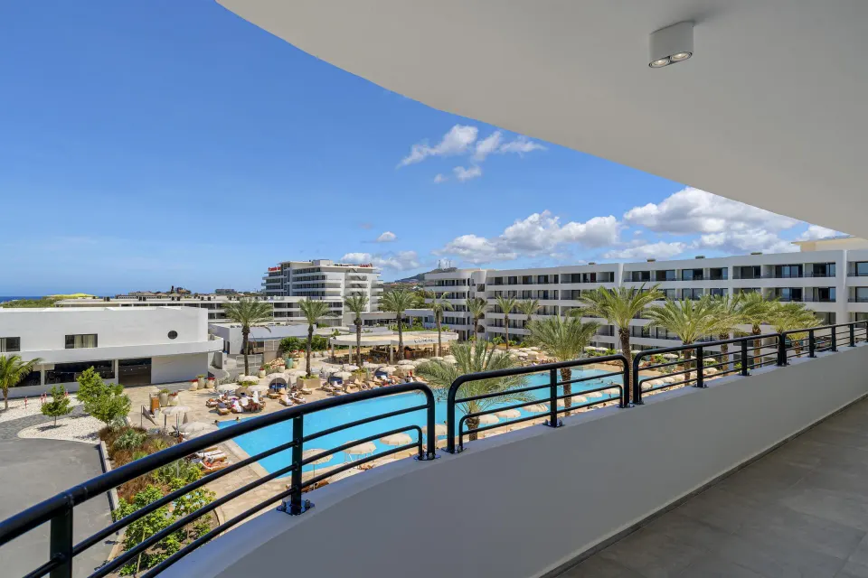 Balcony view of pool, palms, and ocean from a Superior Suite at The Rif at Mangrove Beach Corendon Curacao, Curio.