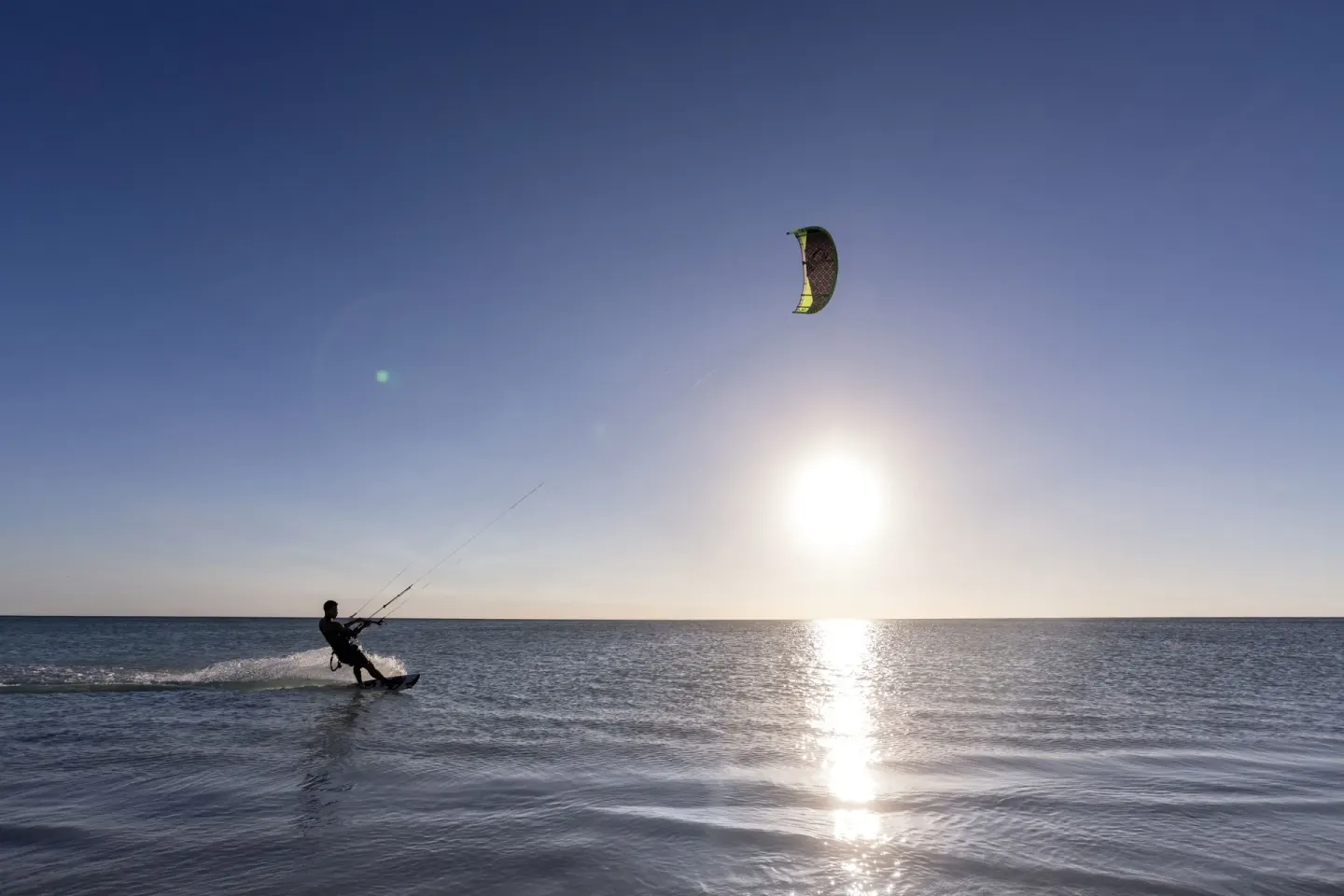 A kiteboarder rides across the ocean at sunset near The Ritz-Carlton, Aruba.