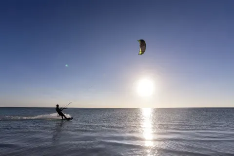 A kiteboarder rides across the ocean at sunset near The Ritz-Carlton, Aruba.