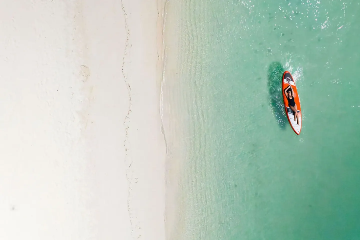A paddleboarder glides over clear water by the beach at The Ritz-Carlton, Aruba.