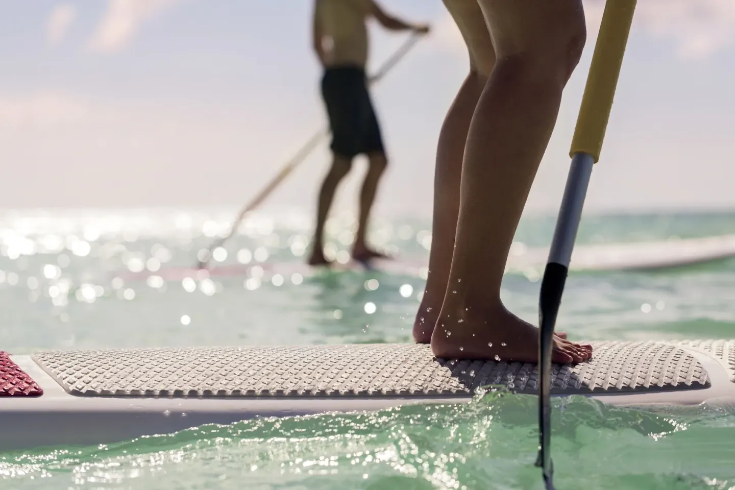 Close-up of paddleboarders standing on turquoise water at The Ritz-Carlton, Aruba.