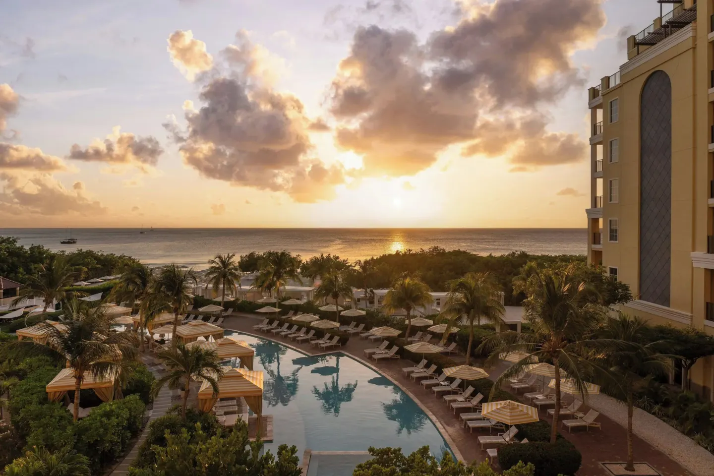 Pool, palm trees and ocean sunset view at The Ritz-Carlton, Aruba.