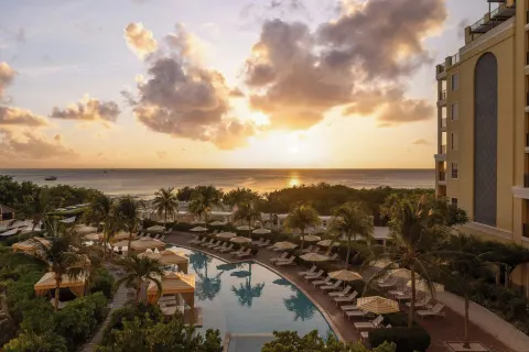 Pool, palm trees and ocean sunset view at The Ritz-Carlton, Aruba.