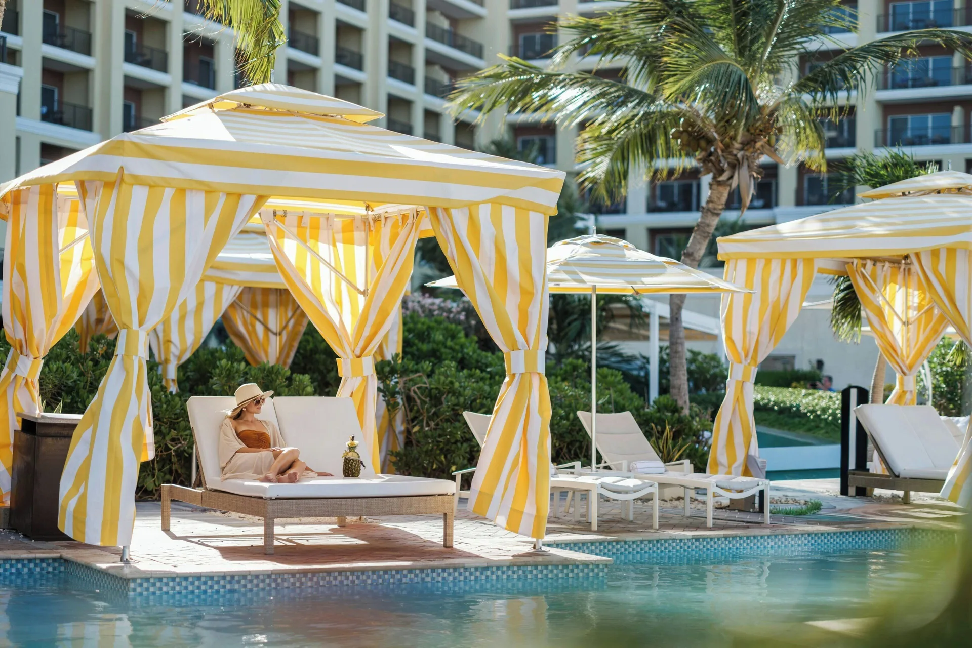 Poolside striped cabanas and loungers beside the resort building at The Ritz-Carlton, Aruba.