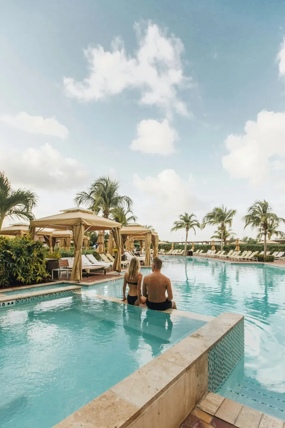 Resort pool with cabanas and palm trees at The Ritz-Carlton, Aruba.