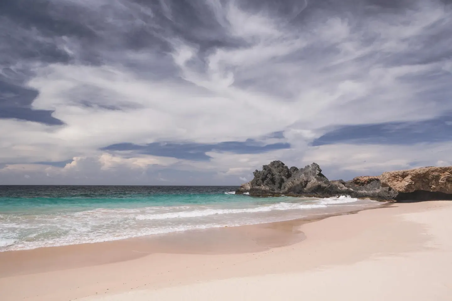 Sandy beach with turquoise surf and rocky shoreline at The Ritz-Carlton, Aruba.