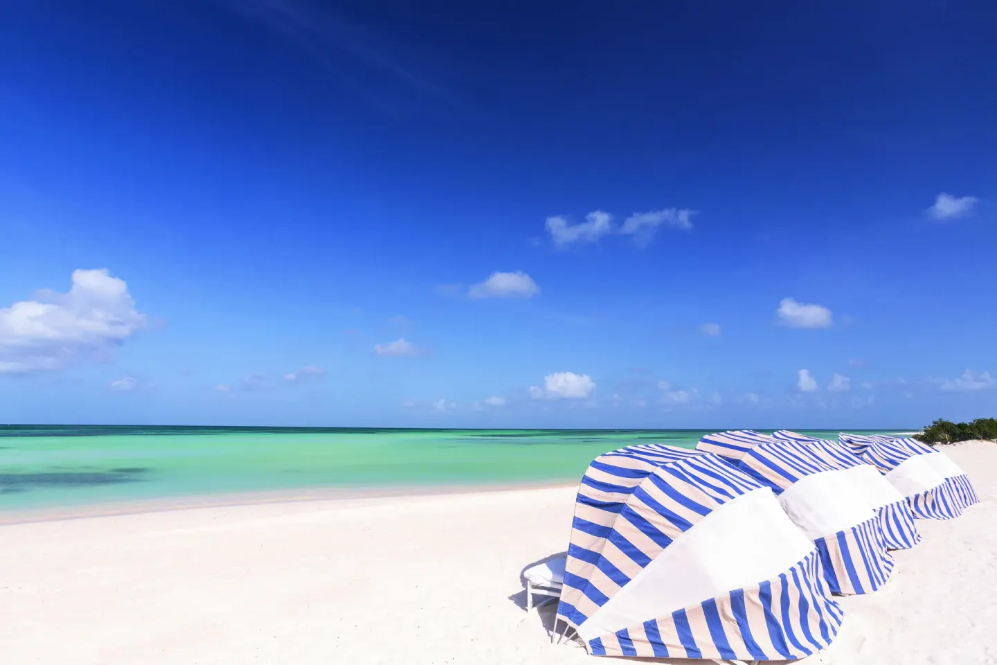 Striped beach cabanas beside turquoise water at The Ritz-Carlton, Aruba.