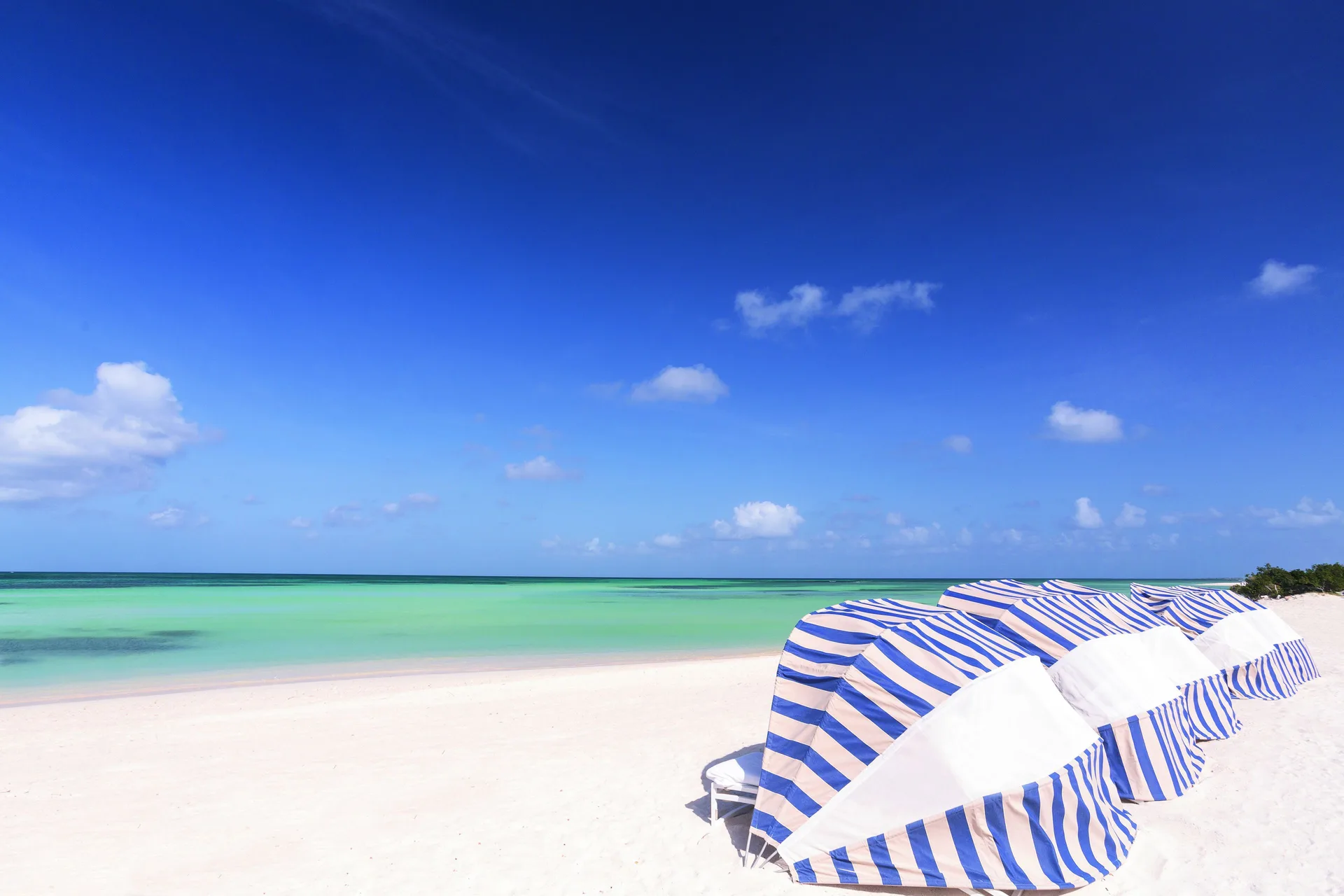 Striped beach cabanas beside turquoise water at The Ritz-Carlton, Aruba.