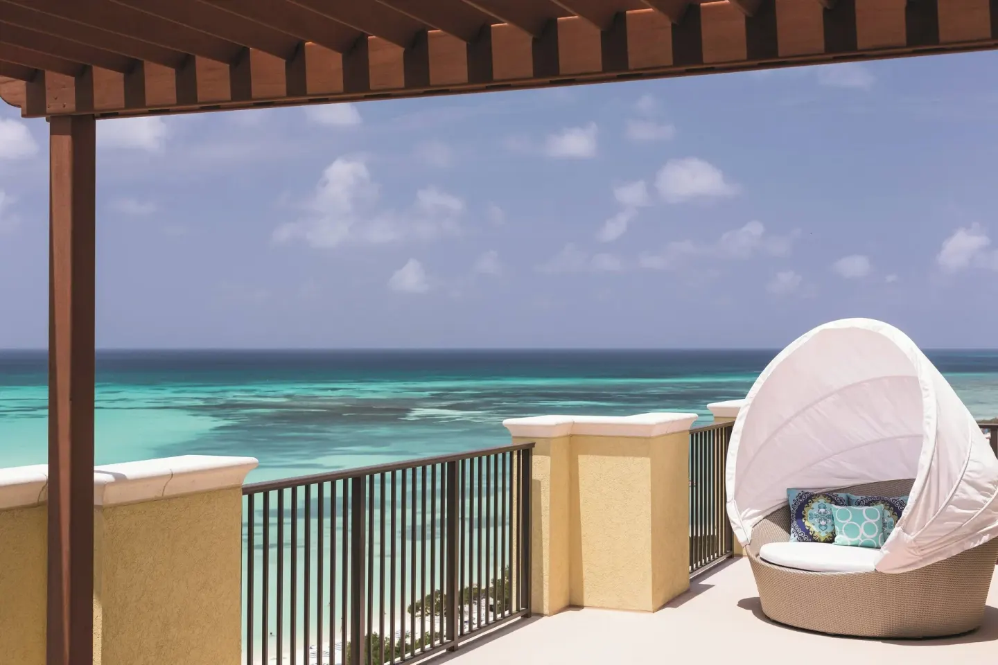 Oceanfront balcony with a round lounge chair and turquoise sea at The Ritz-Carlton, Aruba.
