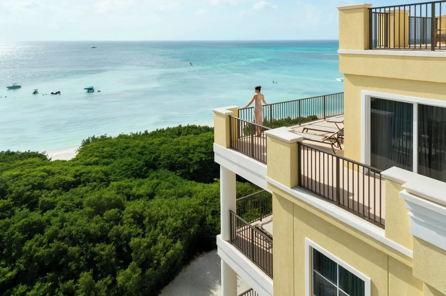 Oceanfront suite terraces overlooking the beach and turquoise water at The Ritz-Carlton, Aruba.