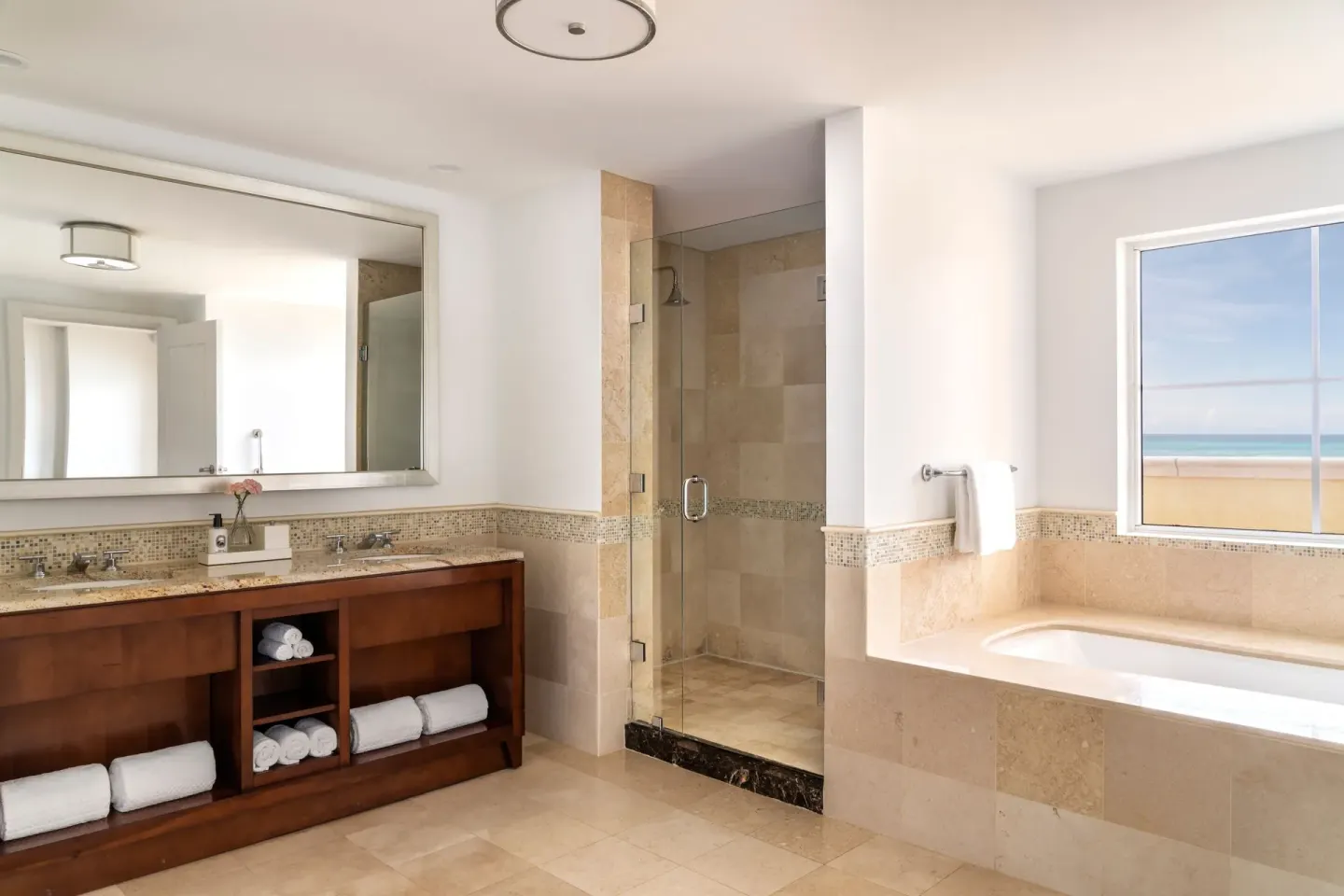 Oceanfront deluxe suite bathroom at The Ritz-Carlton, Aruba with vanity, shower, and soaking tub.