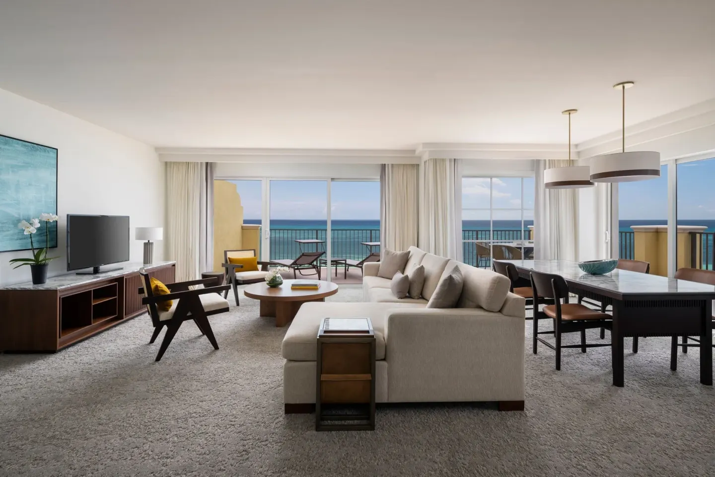 Oceanfront deluxe suite living and dining area at The Ritz-Carlton, Aruba with balcony views.