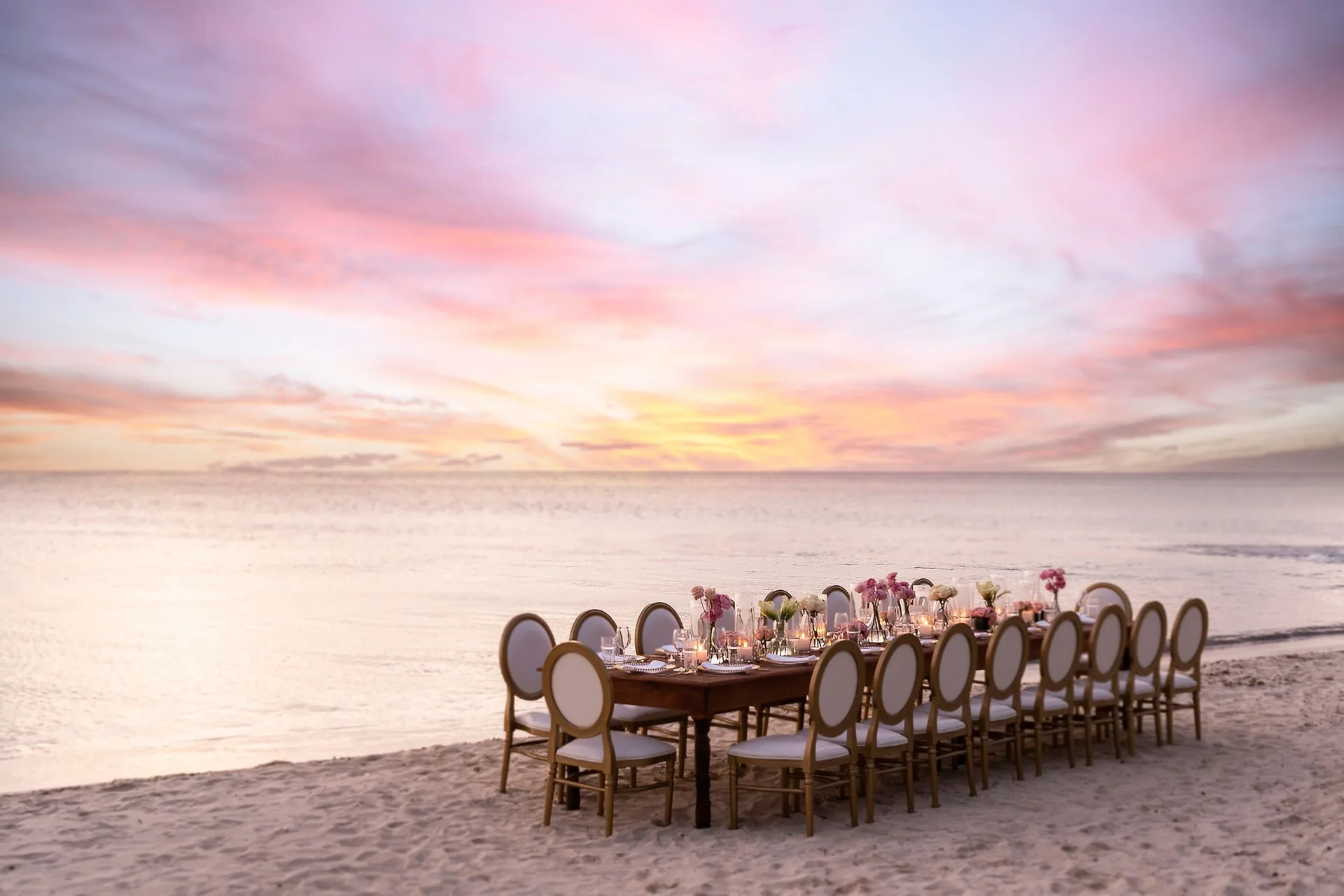 Long beach dinner table set at sunset at The Ritz-Carlton, Aruba.