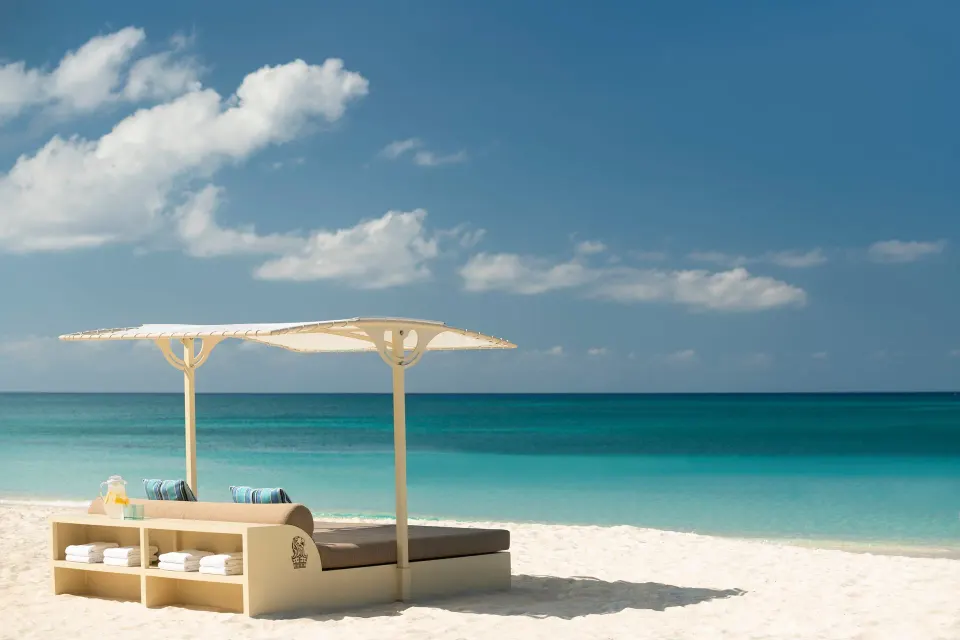 Beach daybed on white sand beside turquoise water at The Ritz-Carlton, Grand Cayman.