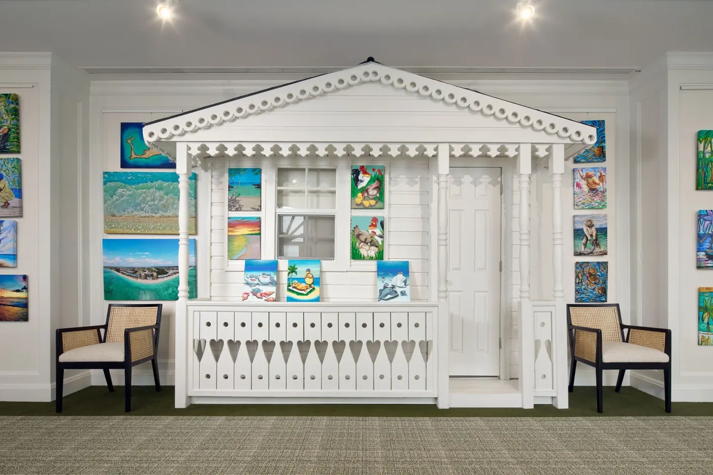 White cottage-style art display with colorful paintings at The Ritz-Carlton, Grand Cayman.