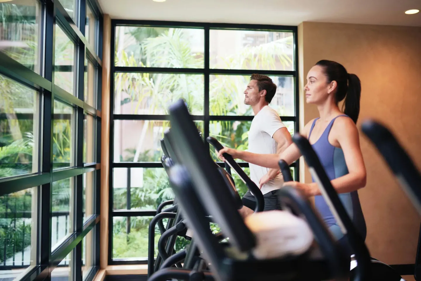 Guests using cardio machines beside tall windows at The Ritz-Carlton, Grand Cayman.