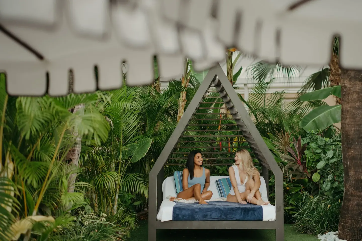 Two guests relaxing on a garden daybed at The Ritz-Carlton, Grand Cayman.