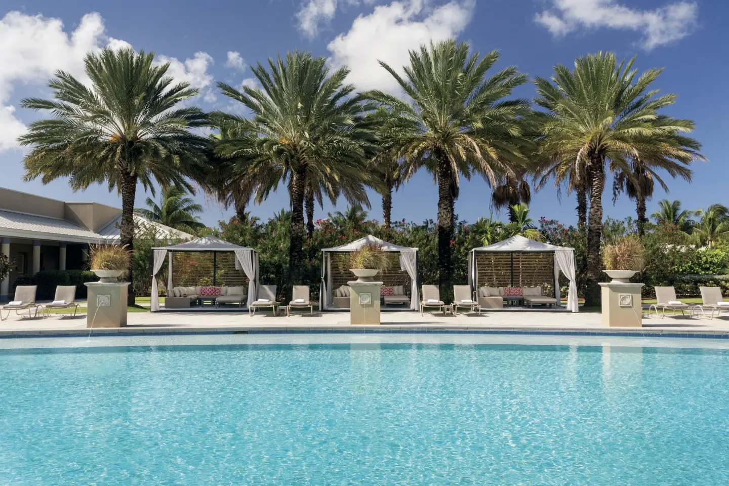 Poolside cabanas lined beneath palm trees at The Ritz-Carlton, Grand Cayman.