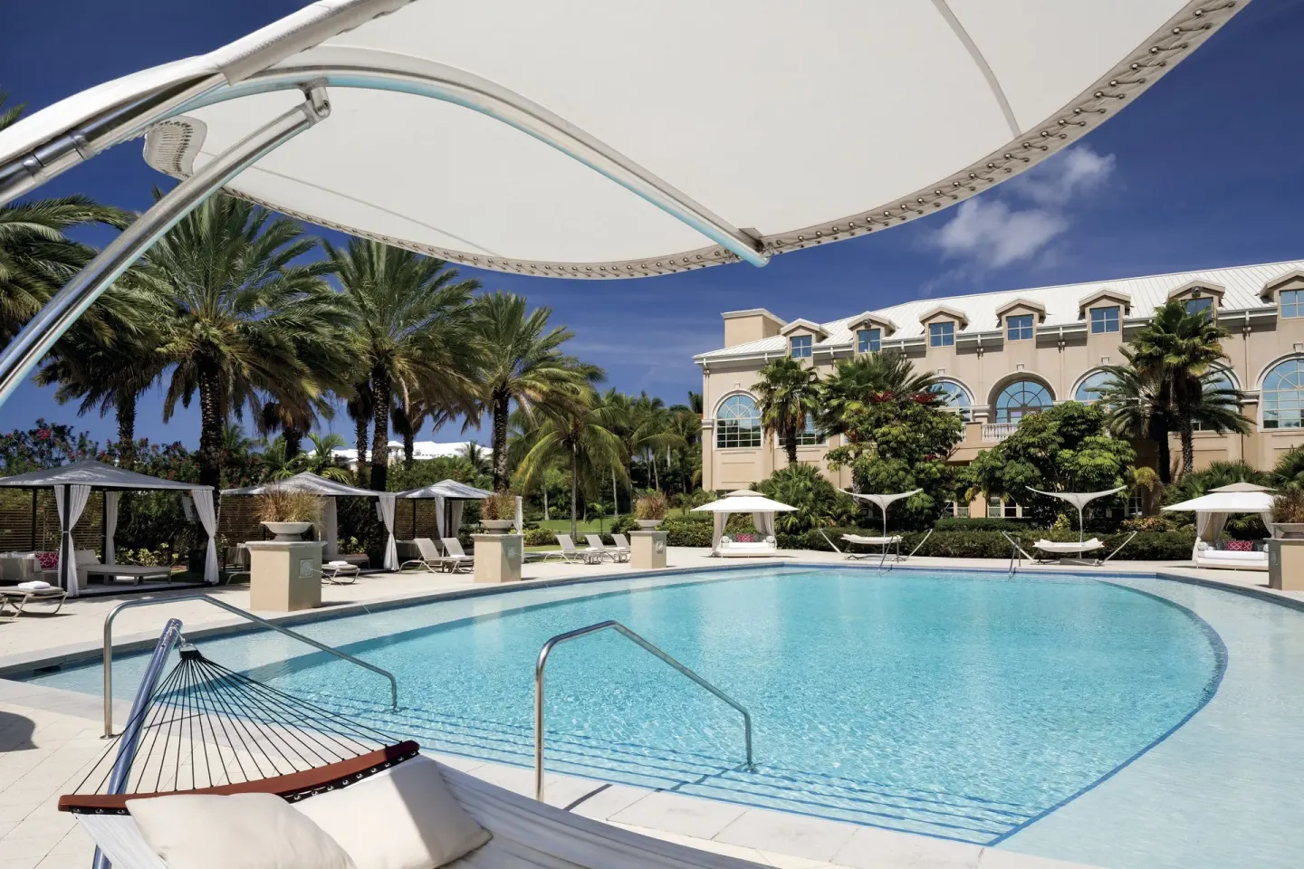Resort pool with shaded hammock and cabanas at The Ritz-Carlton, Grand Cayman.