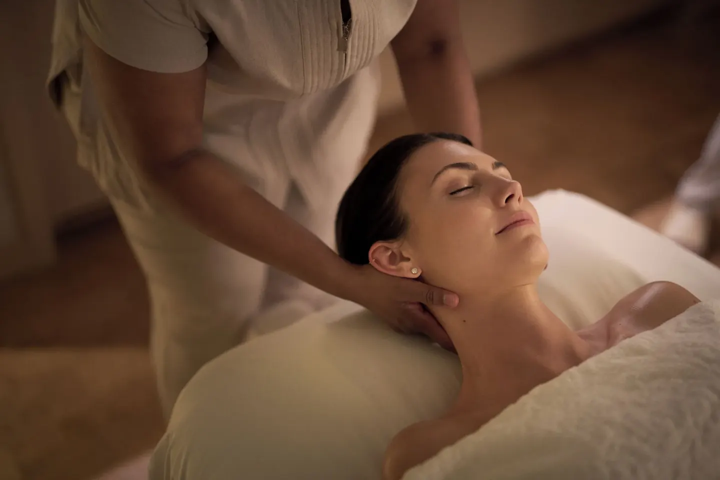 Spa therapist massages a guest's neck on a treatment bed at The Ritz-Carlton, Grand Cayman.