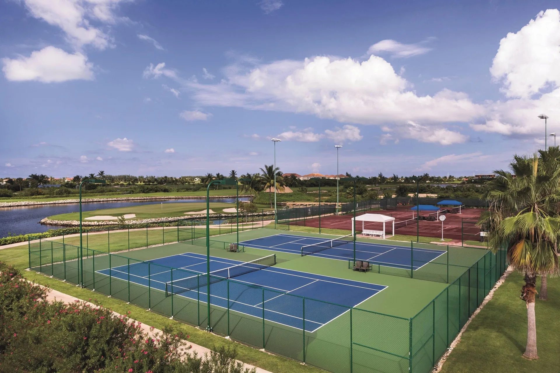 Fenced tennis courts and surrounding resort grounds at The Ritz-Carlton, Grand Cayman.