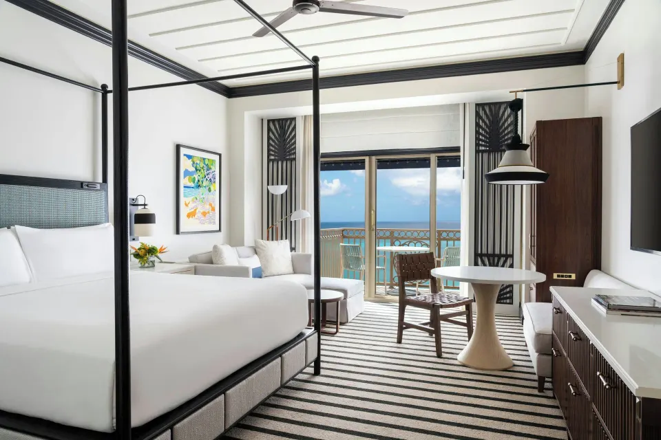 Club Room king bed with seating area and ocean balcony at The Ritz-Carlton, Grand Cayman.