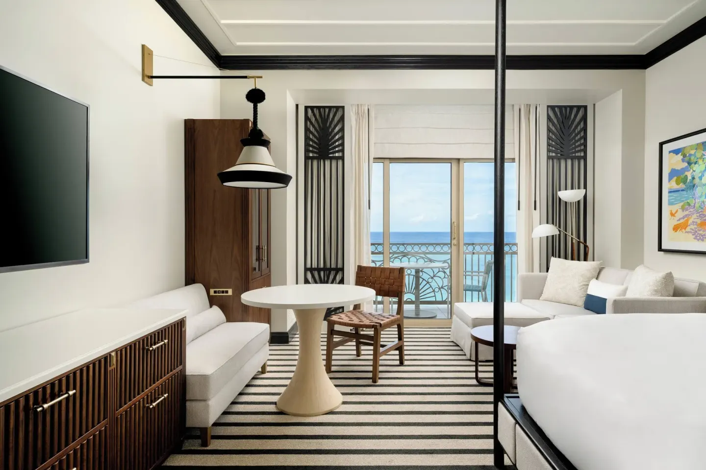 Oceanfront balcony room with sofa, table, and king bed at The Ritz-Carlton, Grand Cayman.