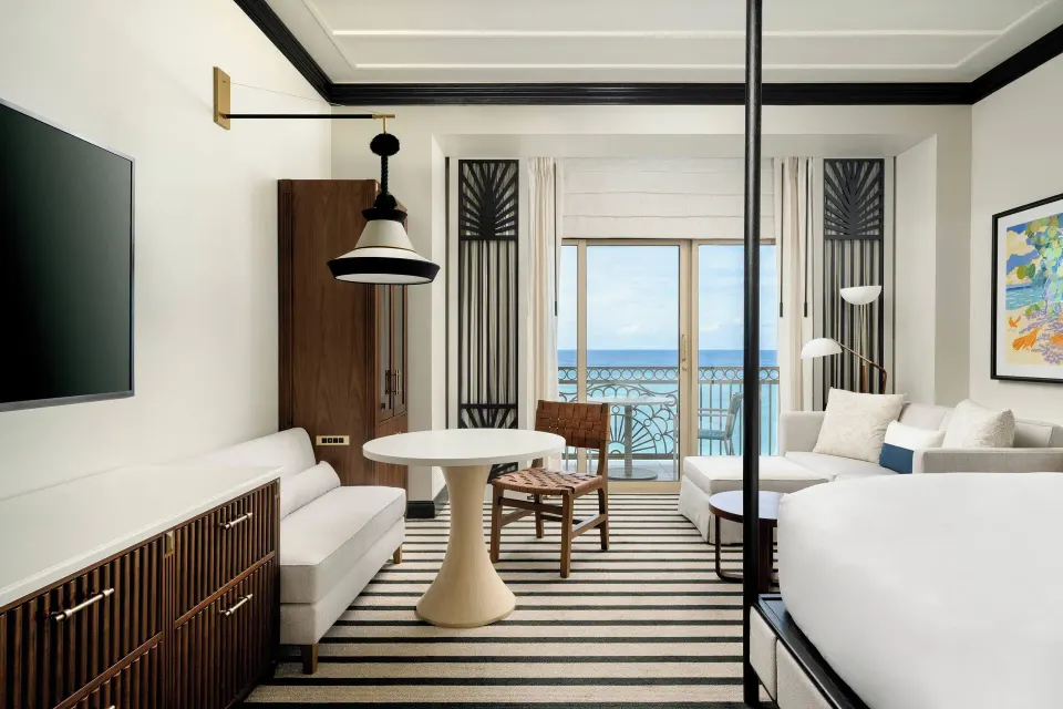 Oceanfront balcony room with sofa, table, and king bed at The Ritz-Carlton, Grand Cayman.