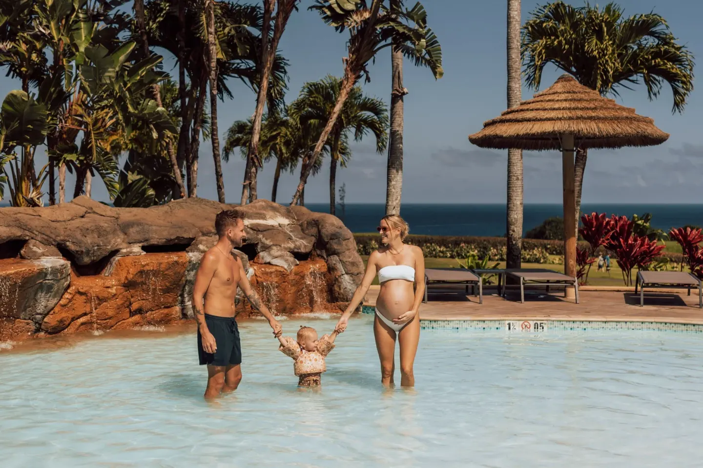 Family wading in the resort pool at The Ritz-Carlton Maui, Kapalua.
