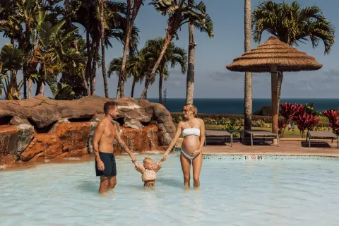 Family wading in the resort pool at The Ritz-Carlton Maui, Kapalua.