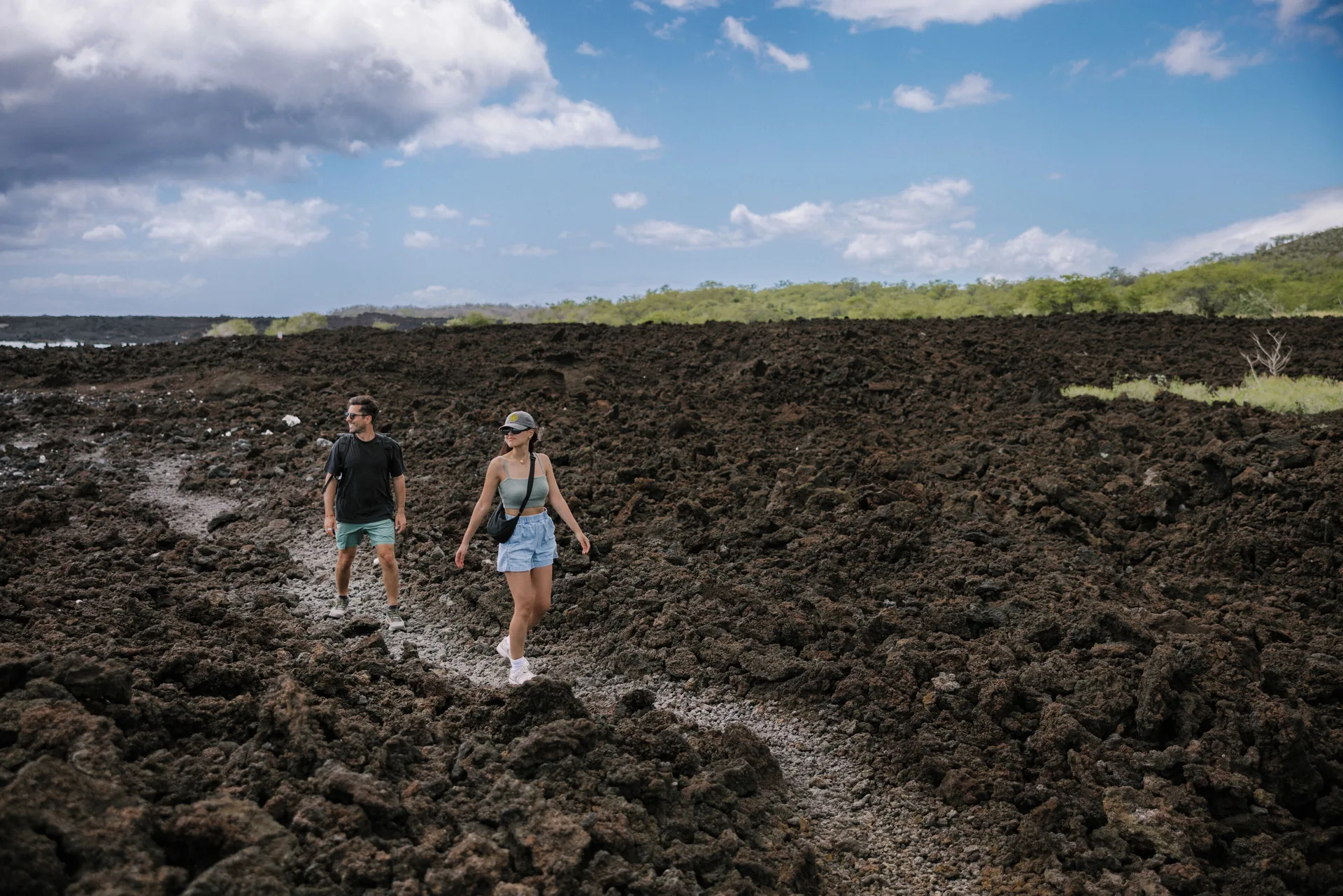 Two people hike across a lava rock trail near The Ritz-Carlton Maui, Kapalua.