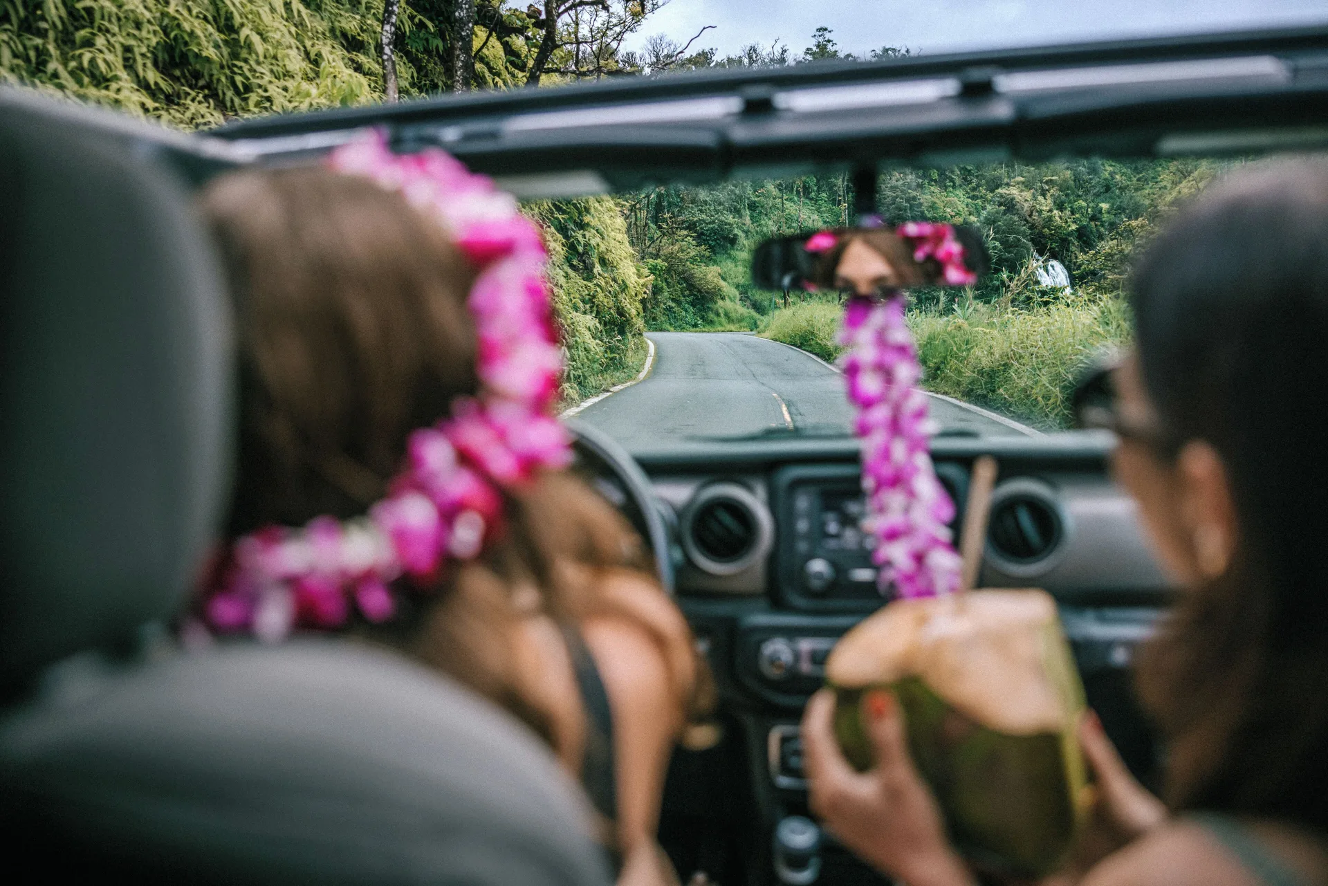 Guests ride in an open vehicle on a green coastal road near The Ritz-Carlton Maui, Kapalua.