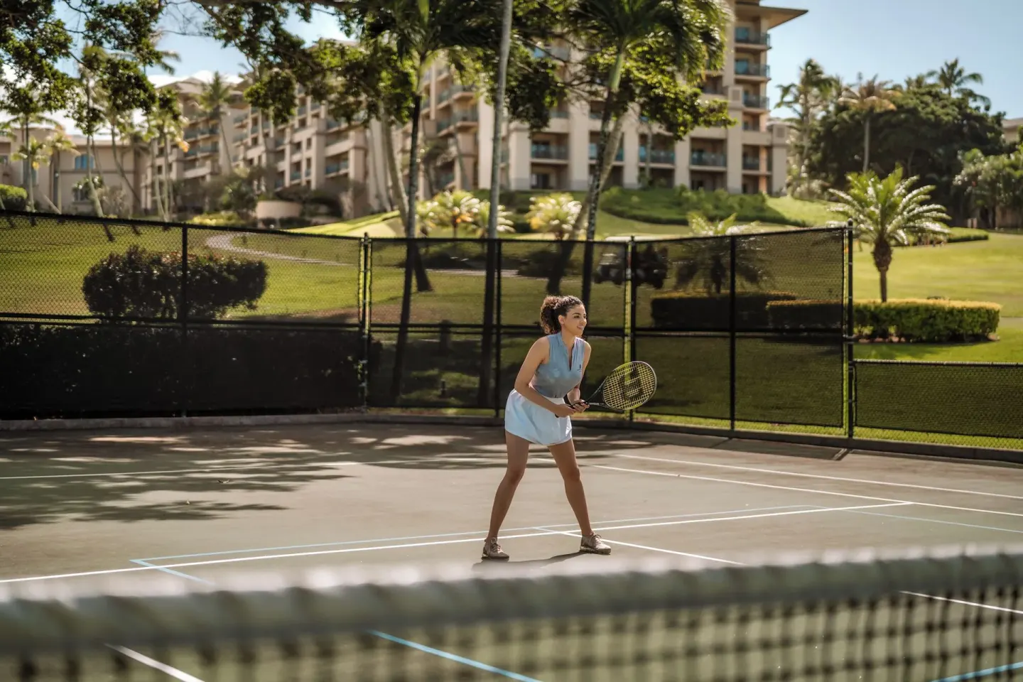 A guest plays tennis on an outdoor court at The Ritz-Carlton Maui, Kapalua.