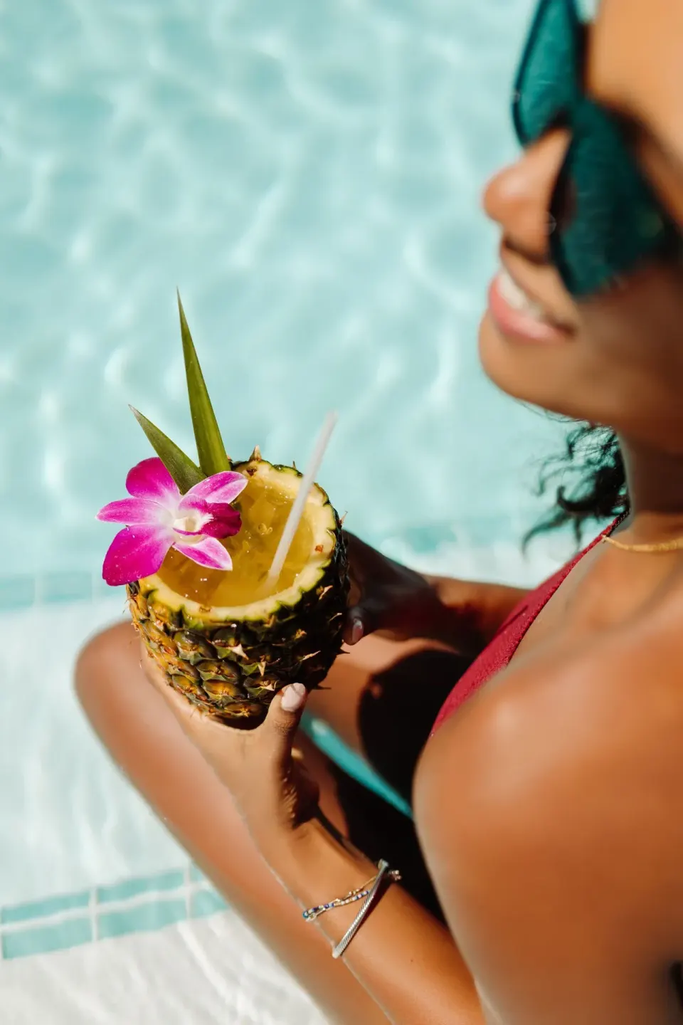 Guest holding a pineapple cocktail by the pool at The Ritz-Carlton Maui, Kapalua.