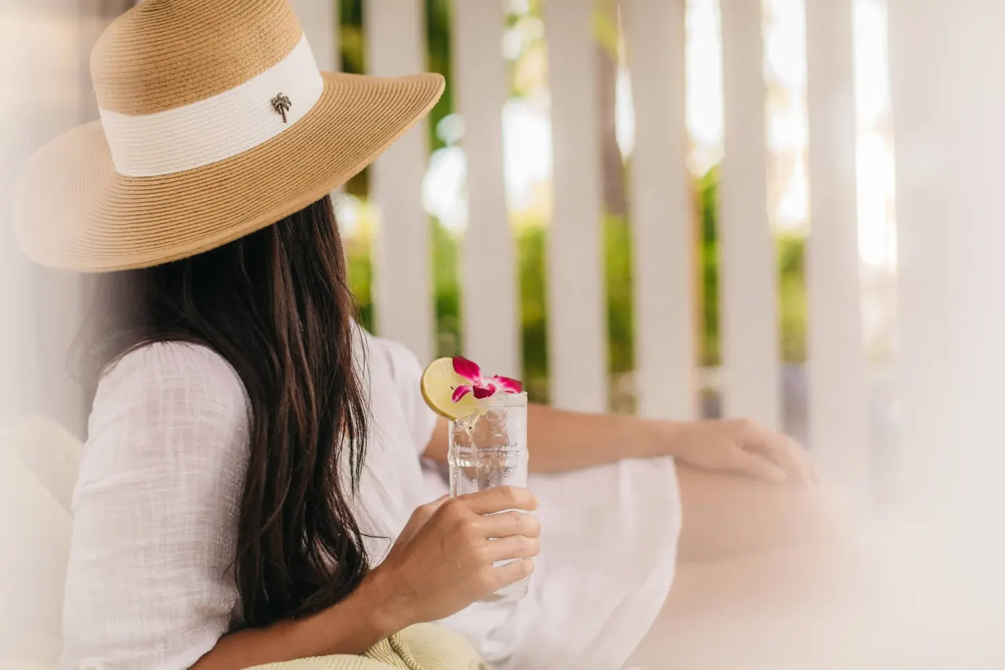 Guest in a sun hat holding a drink at The Ritz-Carlton Maui, Kapalua.