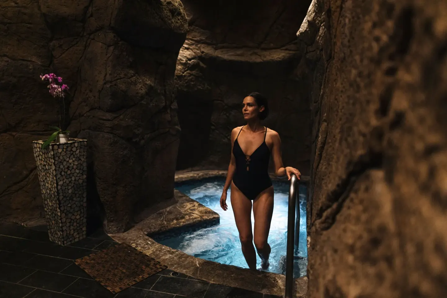 A guest steps into a rock-walled spa pool at The Ritz-Carlton Maui, Kapalua.