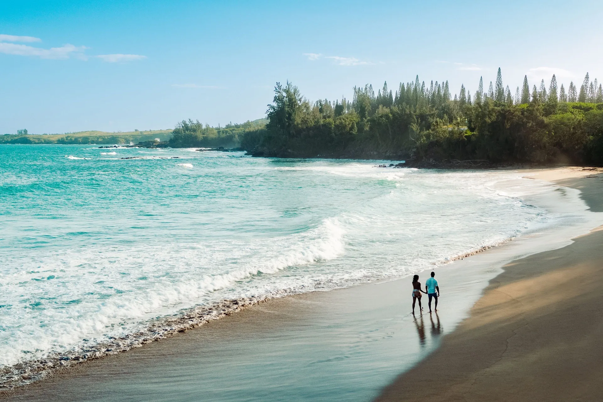 Two people walking along the shoreline at The Ritz-Carlton Maui, Kapalua.