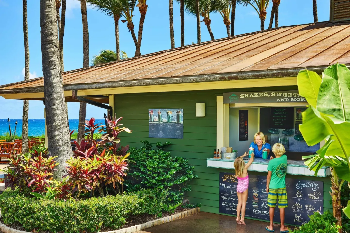Burger Shack counter with guests beside palm trees at The Ritz-Carlton Maui, Kapalua.