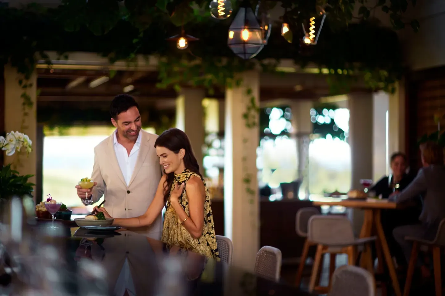 Guests enjoy cocktails at a softly lit bar at The Ritz-Carlton Maui, Kapalua.