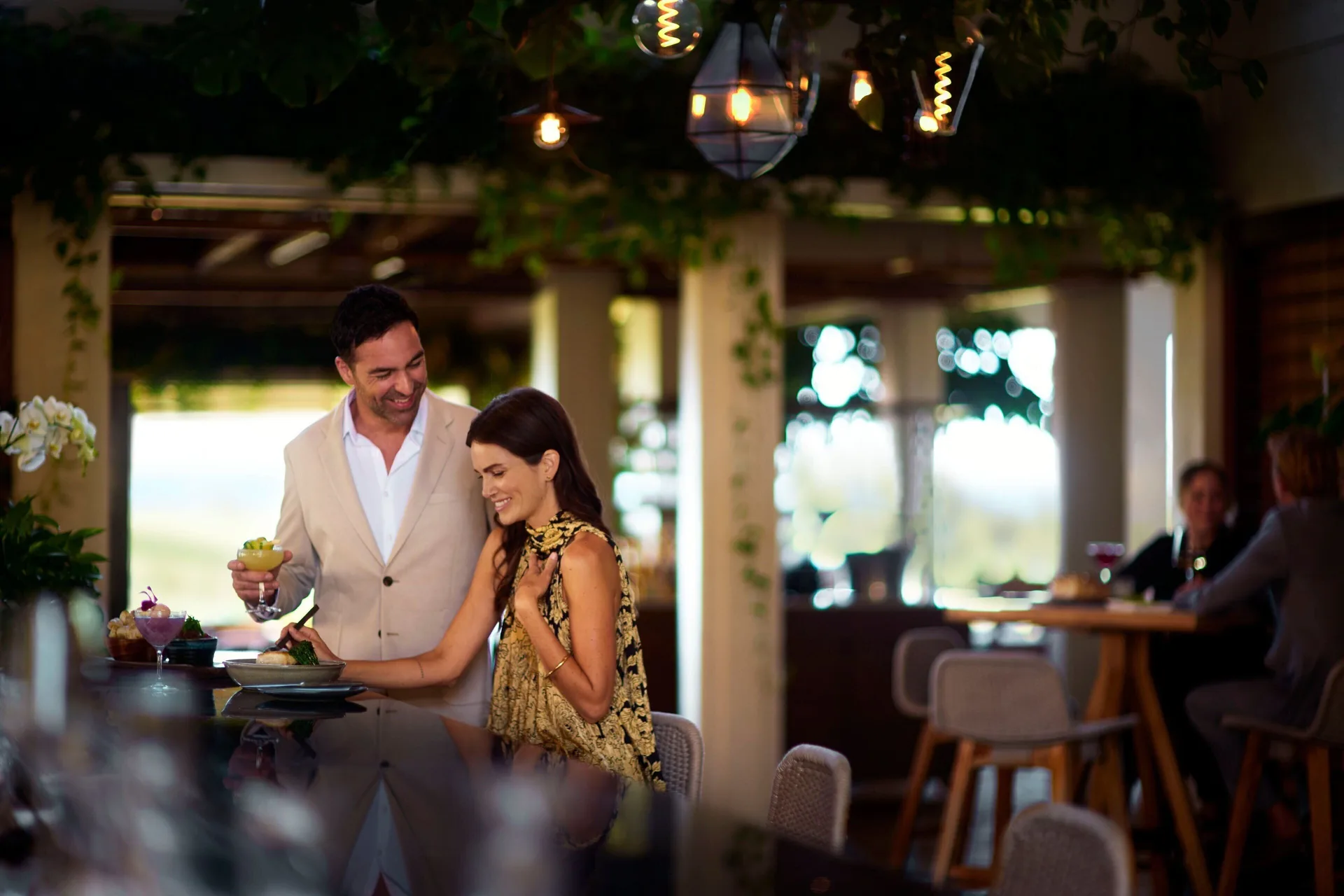 Guests enjoy cocktails at a softly lit bar at The Ritz-Carlton Maui, Kapalua.